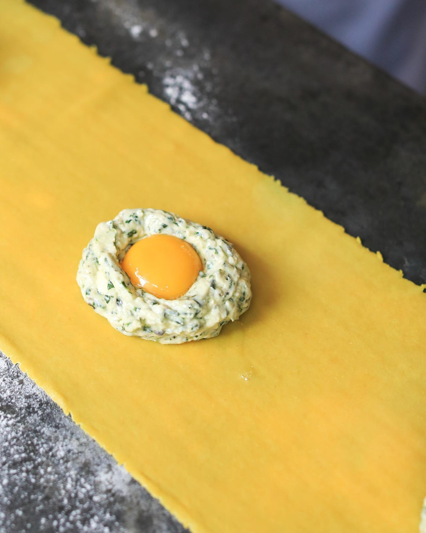 A deep golden Neapolitan pizza with a puffed, charred cornicione on a marble worktop.