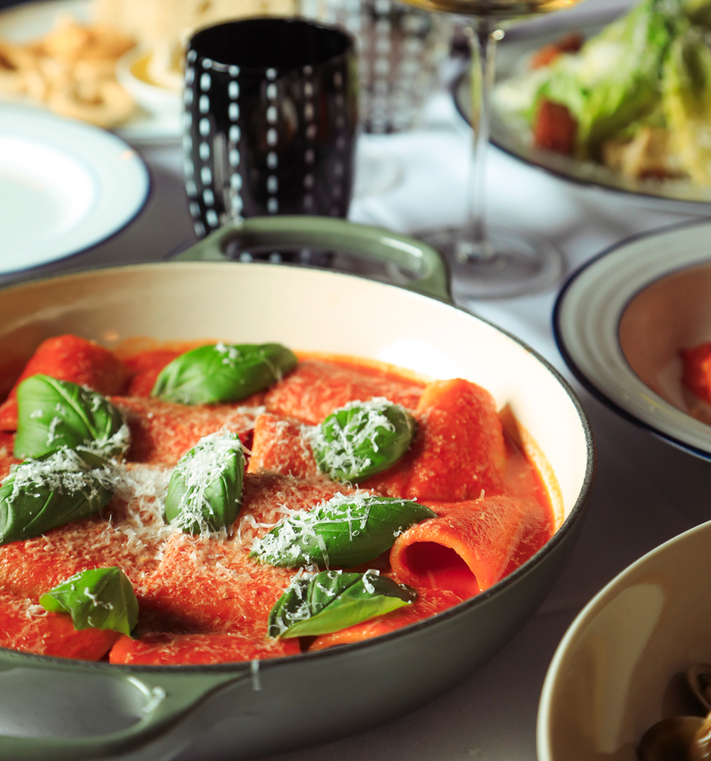 A pizza topped with roasted tomatoes, ribbons of mozzarella and a spiral of basil oil.
